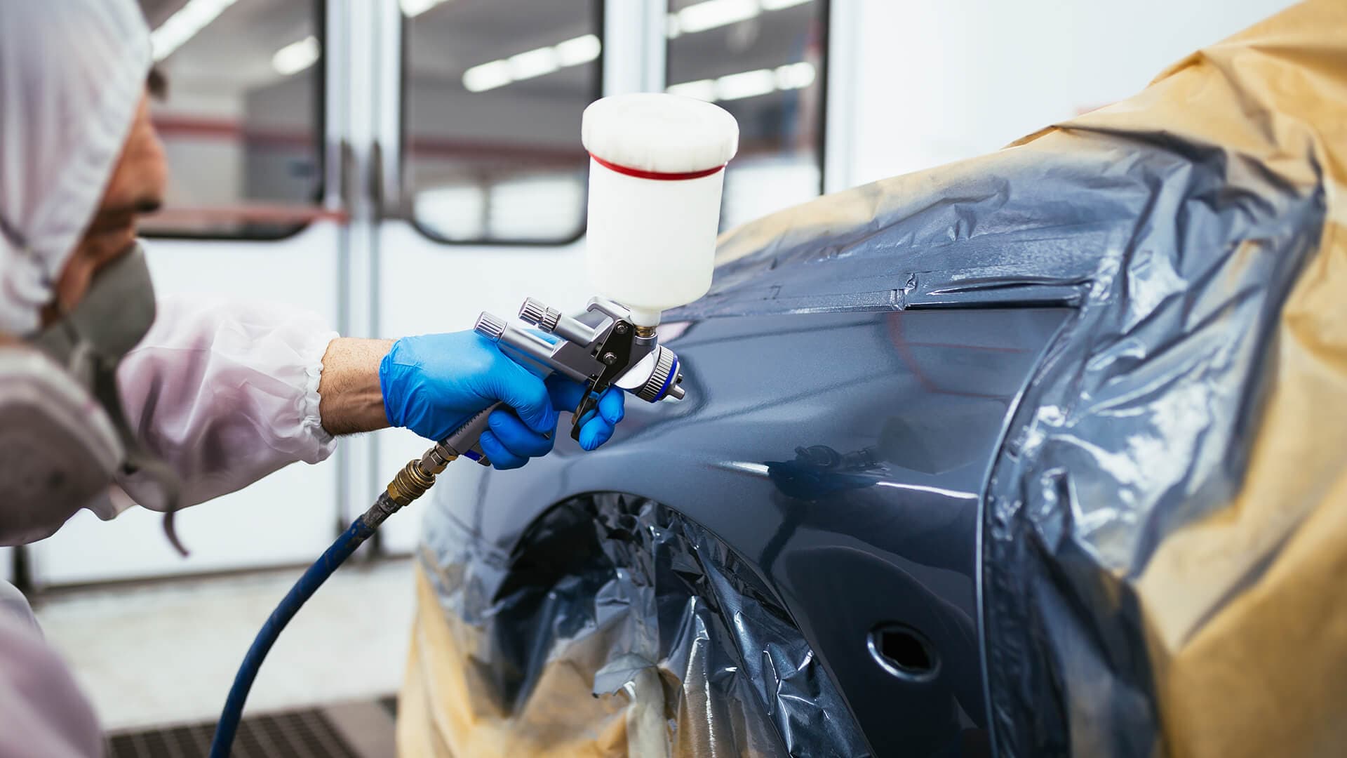 Technician painting a car at Supreme Kustom Collision in Ontario, California